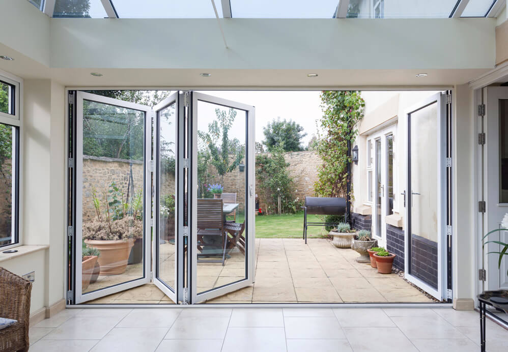 White aluminium bifold partially open leading out onto garden