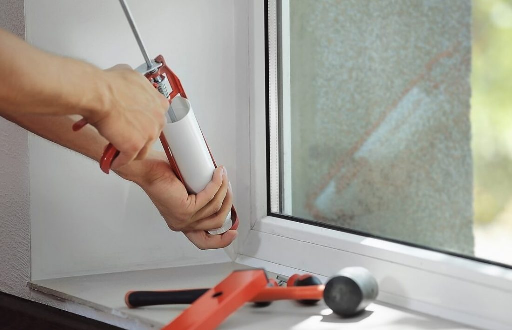 A window repair man with a sealant gun