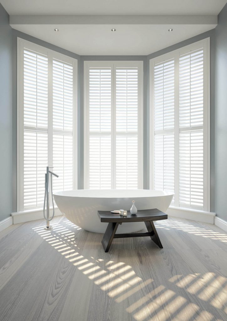 Internal view of bathroom with privacy shutters fitted to the large bay windows
